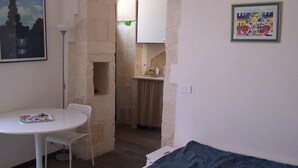 A small room with a white table, a chair, a bed, a painting, and a framed picture on the wall. - Palazzolo Acreide Charming cottage for two people !!  (Palazzolo Acreide)