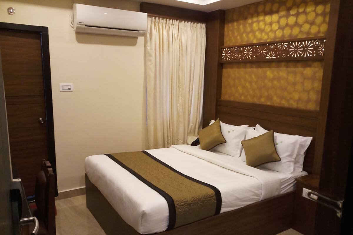 A neatly made bed with white and brown bedding, a wooden headboard, and a decorative panel on the wall.