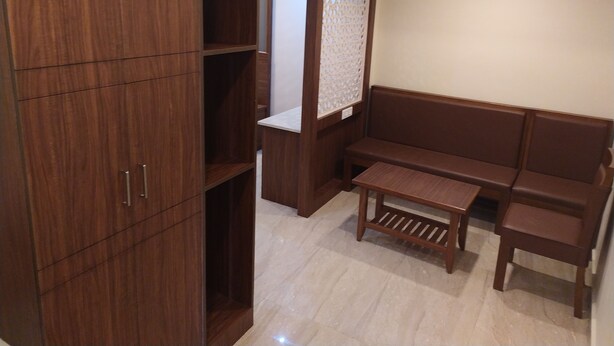 A room with a wooden wardrobe, a bench, and a small table. - Hotel White Boutique (Puducherry)