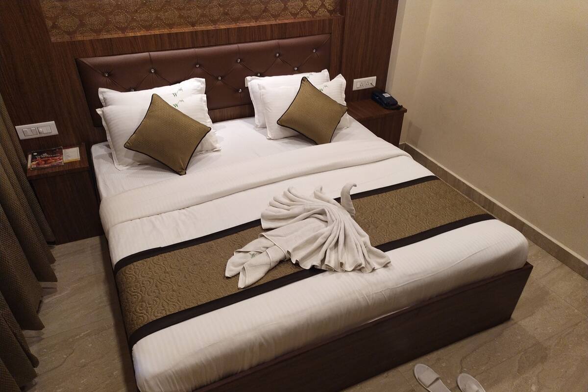 A neatly made bed with a brown headboard, white bedding, and two brown pillows.