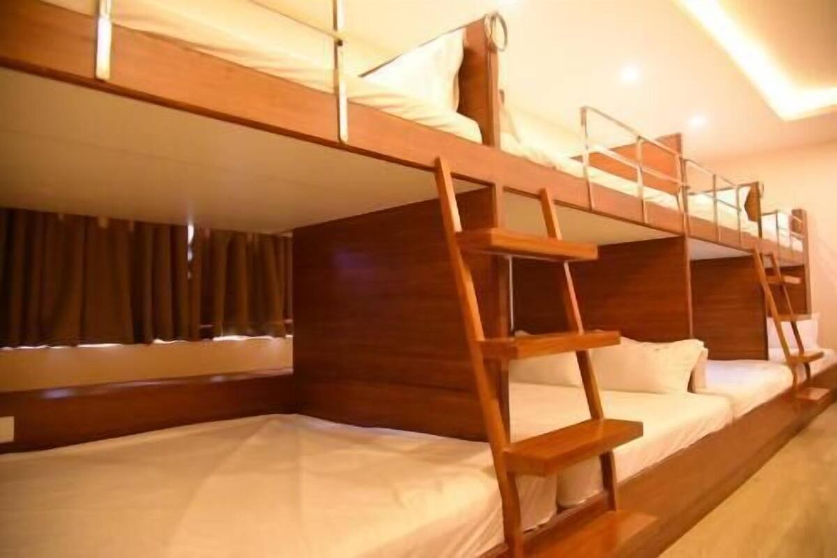 A bunk bed room with wooden railings and white bedding.