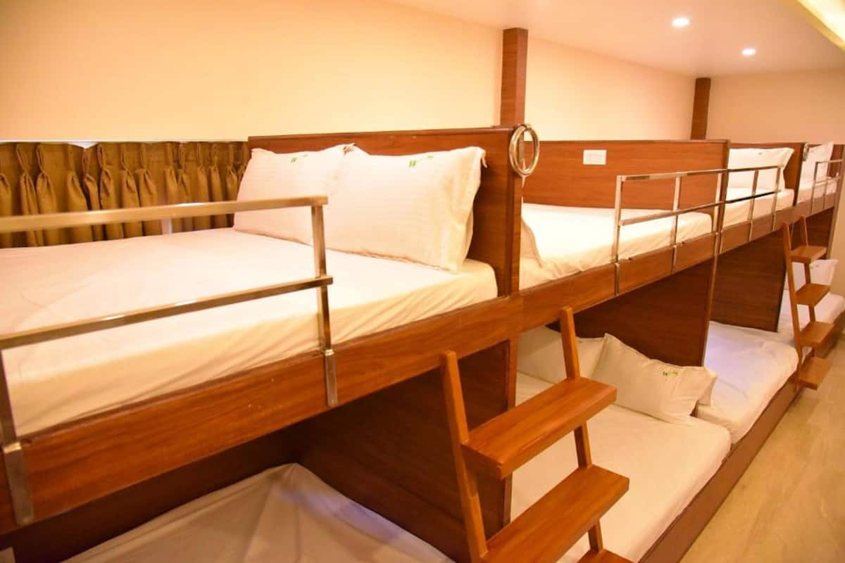 A bunk bed room with wooden frames and white bedding.