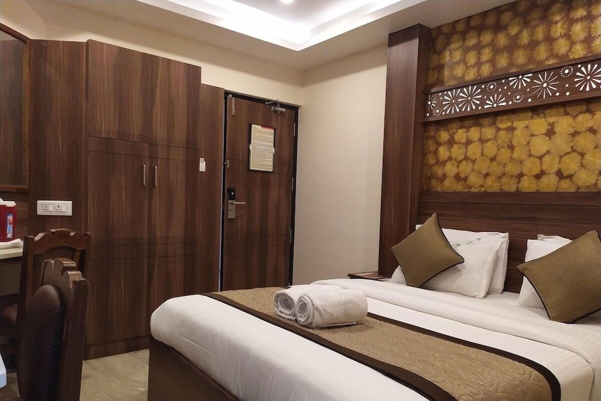 Quarto de hotel com uma cama grande, um guarda-roupa e uma secretária com cadeira.