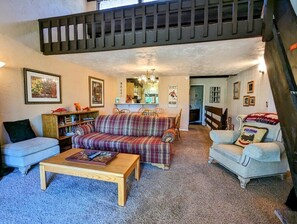 A cozy living room with a sofa, armchairs, a coffee table, and a bookshelf.