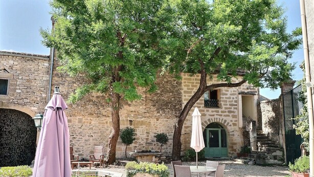 An outdoor patio with stone walls, a green door, and wicker furniture.