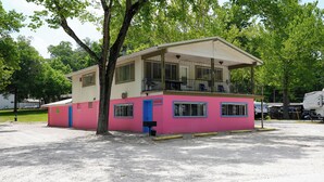 Un edificio rosa y blanco con balcón y un porche cubierto.