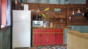 Una cocina con un refrigerador blanco, un microondas y armarios rojos. Hay un pez colgado en la pared y un letrero que dice 'Eat Fish and Chips'.