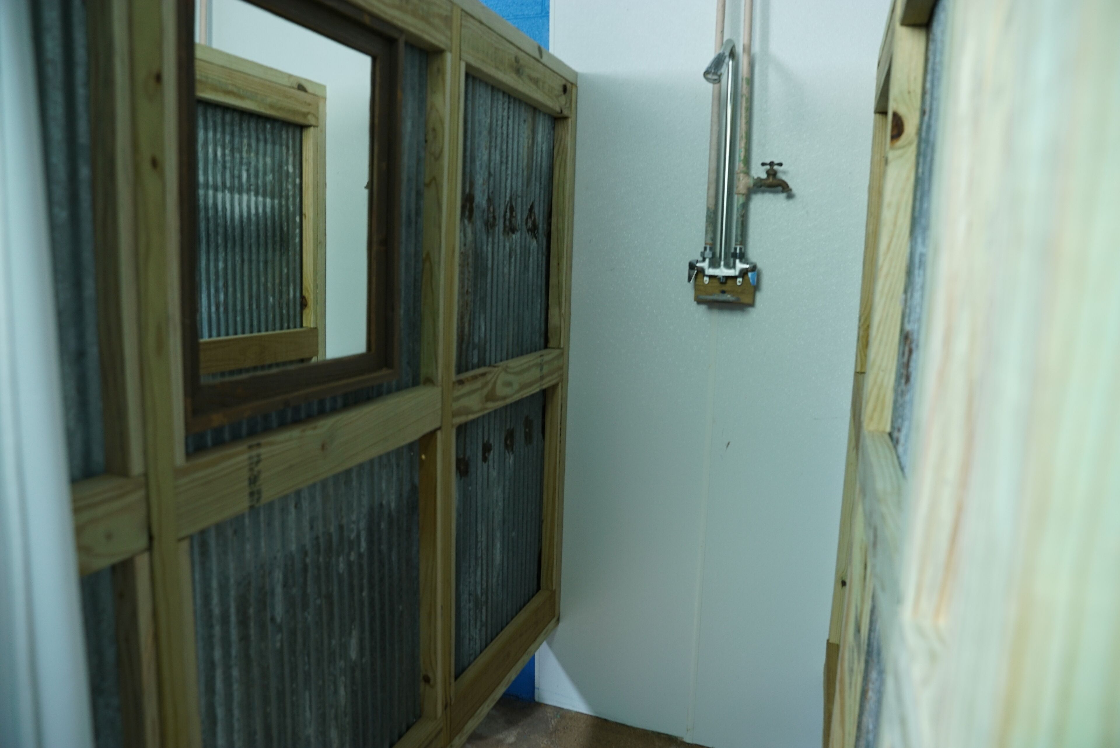 Un couloir étroit, doté de fenêtres à cadre en bois et d’une conduite métallique fixée au mur.