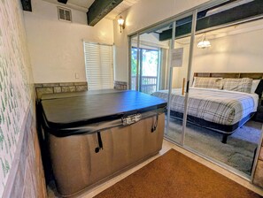 A room with a bed, a massage table, and a sliding glass door leading to a balcony.