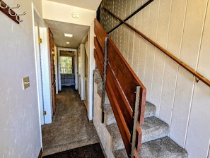 Ein Flur, der zu einer Treppe mit hölzernem Geländer und einer Wand mit Musterung führt.