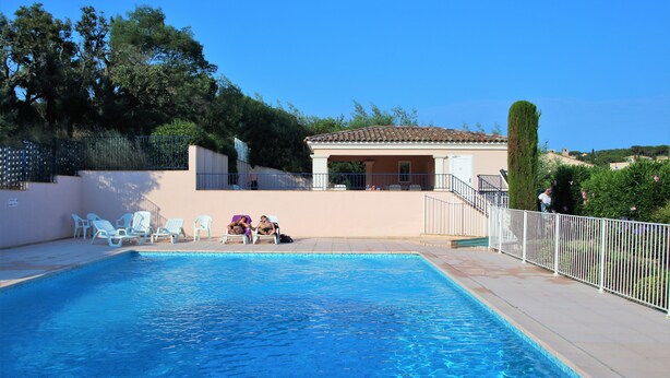 A swimming pool with lounge chairs and a small building with a tiled roof. - Apartment les Pins Bleus A8 Sainte Maxime near the sea with swimming pool and terrace  (Sainte-Maxime)