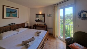 A hotel room with a bed, a bedside table with a lamp, a mirror, a framed picture on the wall, and a balcony with a view. - Apartment les Pins Bleus A8 Sainte Maxime near the sea with swimming pool and terrace  (Sainte-Maxime)