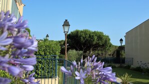 A garden with a pathway, lamp posts, and a building in the background. - Apartment les Pins Bleus A8 Sainte Maxime near the sea with swimming pool and terrace  (Sainte-Maxime)