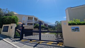 A gated entrance to a building with a clear sky and a sun shining. - Apartment les Pins Bleus A8 Sainte Maxime near the sea with swimming pool and terrace  (Sainte-Maxime)