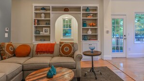 A living room with a sectional sofa, a coffee table, and a bookshelf.