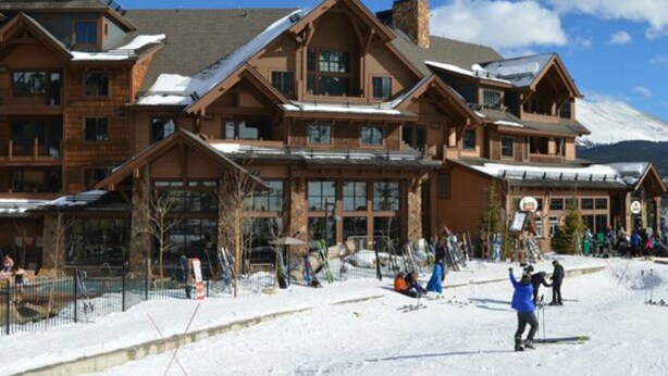 Ein großes Chalet mit mehreren Etagen und einer Skipiste davor.