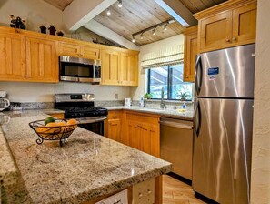 A kitchen with wooden cabinets, stainless steel appliances, granite countertops, and a window with a view. - Relax & Recharge in a Beautiful Snow Summit Townhouse (BIG BEAR LAKE)