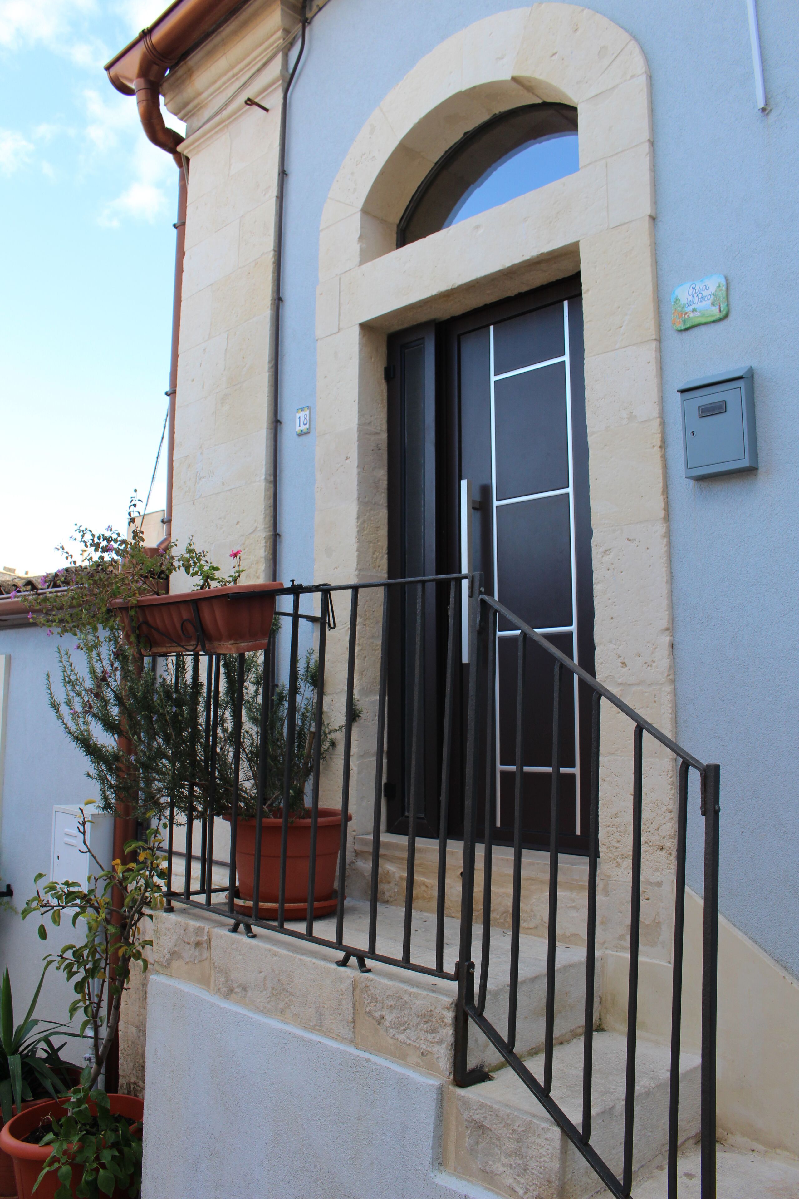 A building with a stone facade, a black door, and a small balcony with a railing.