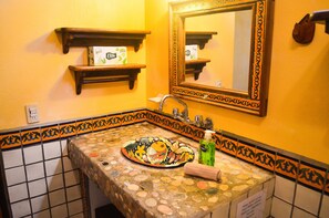 A bathroom with a mosaic sink, a mirror, and two wooden shelves with toiletries. - Authentic pool-side apt studio w/ full kitchen, 1min walk to beach, free yoga (Puerto Escondido)