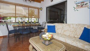 A dining area with a table set for four, a sofa with blue cushions, and a decorative bowl on a woven tray.