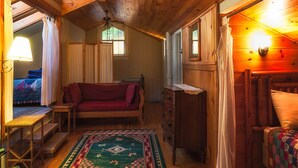 Un interior de cabaña acogedor, con techo de madera, un sofá, un aparador y una ventana.