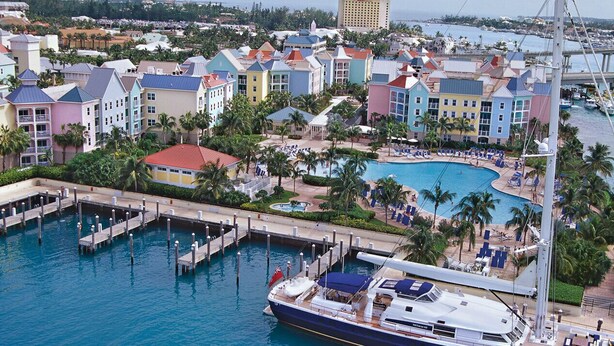 Un puerto deportivo con barcos amarrados, una piscina y edificios de colores.