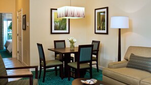Habitación de hotel con comedor que incluye una mesa, sillas, un sofá, una lámpara y cuadros en las paredes.