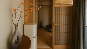 Ein Holzboden, eine Blumenvase, eine Hängeleuchte und eine Schiebetür.