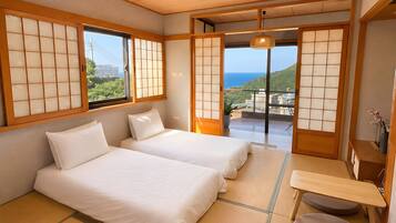 Ein traditioneller japanischer Raum mit Tatami-Böden, zwei Betten, Schiebetüren und Blick auf das Meer.