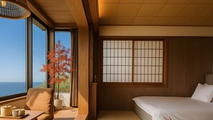 Ein Zimmer mit einem Bett, einem Tisch mit Stuhl, einem Fenster mit Blick und einem traditionellen japanischen Shoji-Bildschirm.