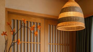 A room with a wooden sliding door, a hanging lamp, and a vase with flowers on a table.
