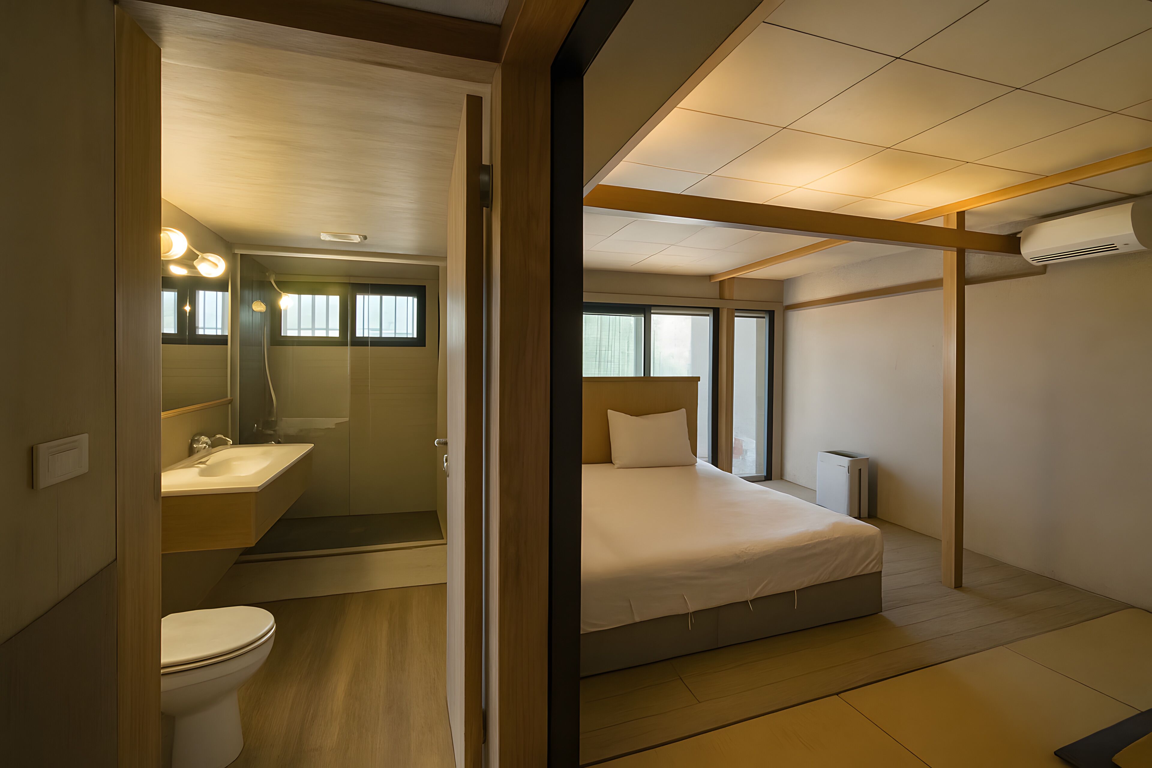 Ein modernes Hotelzimmer mit eigenem Badezimmer, einem Bett und einem Fenster.
