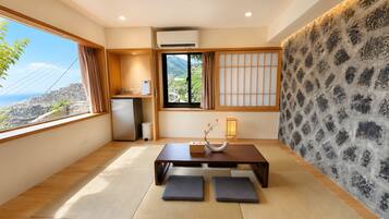 Un interior moderno con esteras de tatami, una mesa de madera, un refrigerador y vistas a un paisaje montañoso.