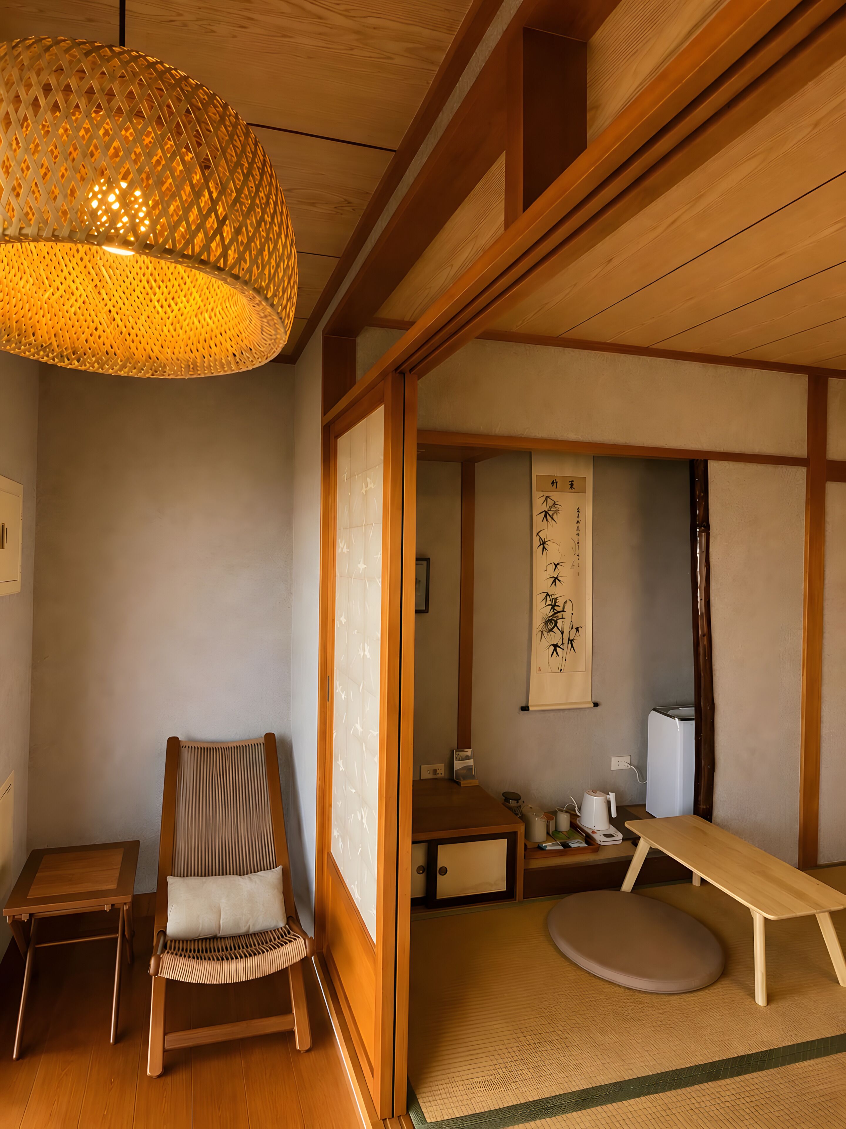 A traditional Japanese room with tatami flooring, a low wooden table, a woven hanging light fixture, and a sliding shoji screen door.