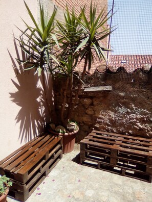 A patio area with wooden benches, a potted plant, and a stone wall.