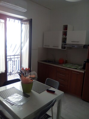 A small kitchen with a dining table, chairs, a sink, and cabinets.