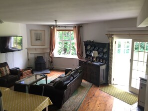 A living room with a fireplace, a sofa, a television, and a window with curtains.
