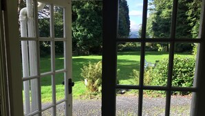 Uitzicht door een glazen deur, met een tuin in de verte.