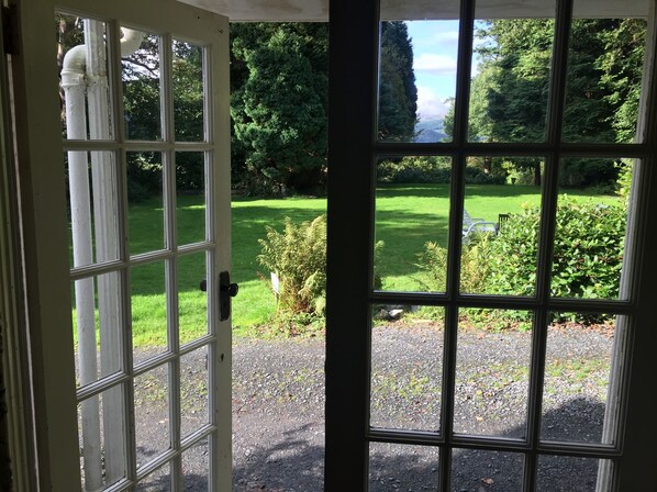 A view through a glass door with a garden visible outside.