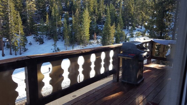 Una terraza de madera con barandilla que da a un bosque nevado.