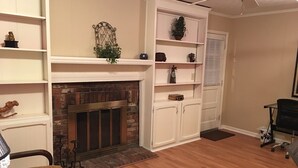 A living room with a fireplace, wooden flooring, white shelving, and a black office chair. - 3br/2bath  2000 sf HOUSE Garage, private yard, & location  1 mile to xway, (Louisville)