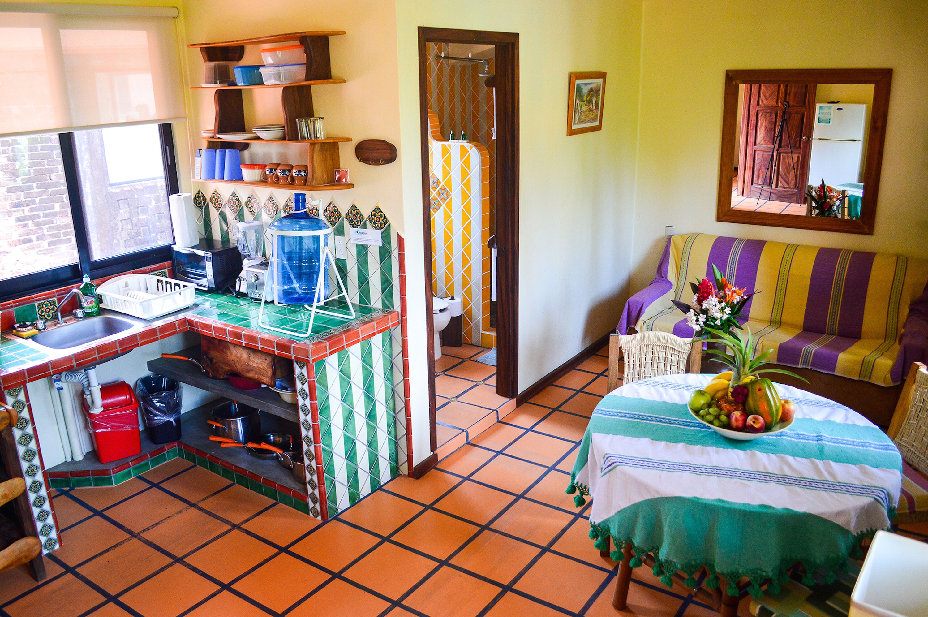 A compact kitchen with a tiled backsplash, a sink, and a dining area with a table set for two.