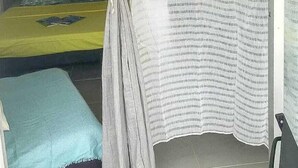 A bedroom with a bed, a bedside table, and a curtain.