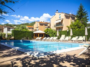 Relax by the resort pool surrounded by lounge chairs and umbrellas, with steps leading into the clear blue water.