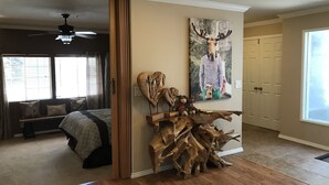 Une pièce comprenant un lit, une sculpture en bois et un tableau représentant un cerf.