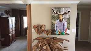 Un salon avec une table basse en bois, un tableau représentant un élan accroché au mur et un pilier en bois.