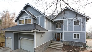 Une maison à deux étages avec un garage, des fondations en pierre et un porche à l’avant.