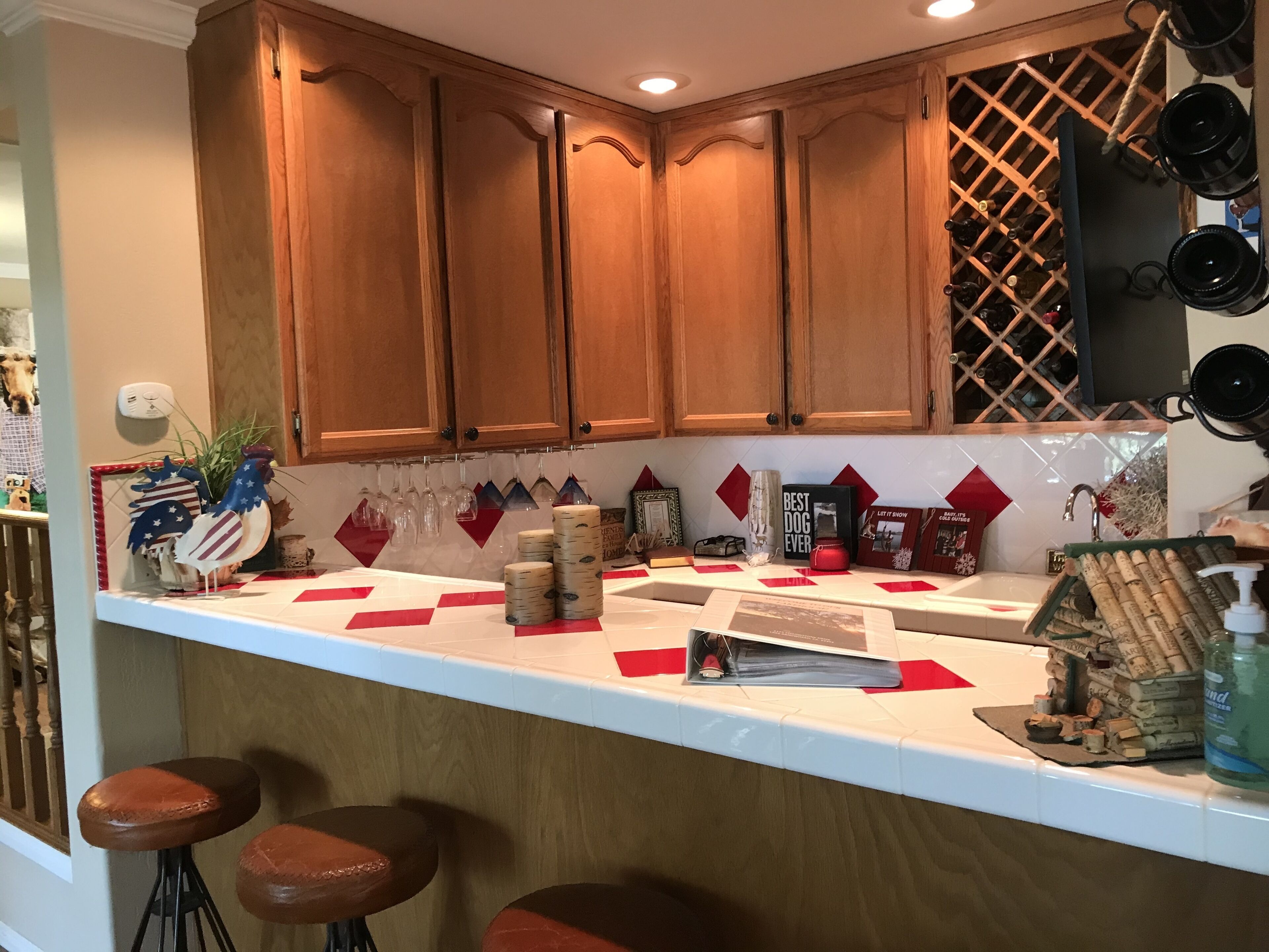 Una cocina con armarios de madera, una alacena para vinos y una zona de bar con taburetes.