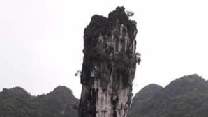 Una gran formación rocosa en el agua, rodeada de colinas.