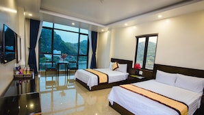 Habitación de hotel con dos camas, un escritorio y un amplio ventanal con vistas a las montañas.